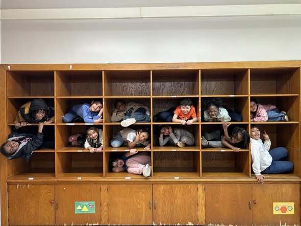Students curled up in cubbies and smiling.