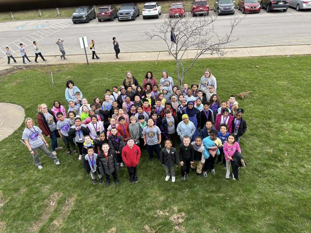 Students standing on the gras and posing in front of JoAnna Connell.