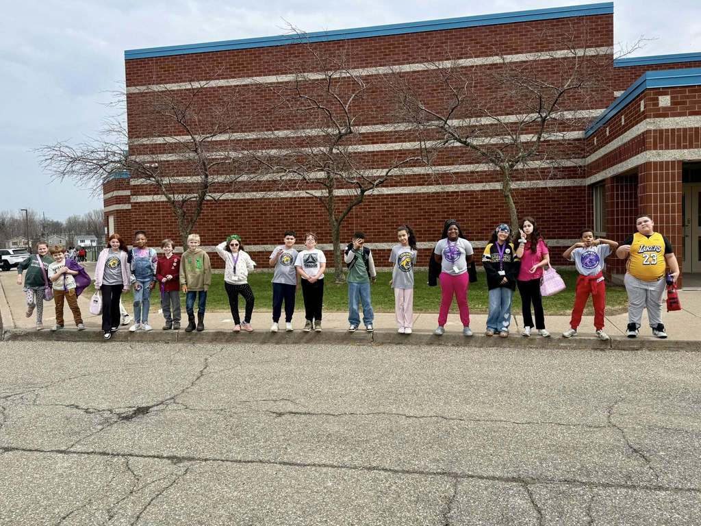 Students standing on the sidewalk in front of JoAnna Connell and they are smiling. 