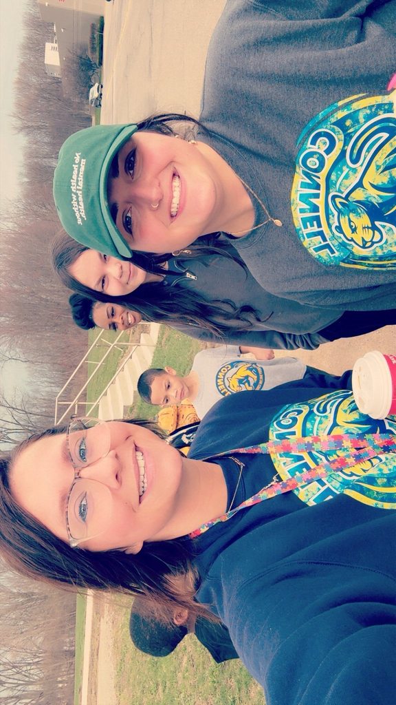 Staff and students behind them outside smiling. 