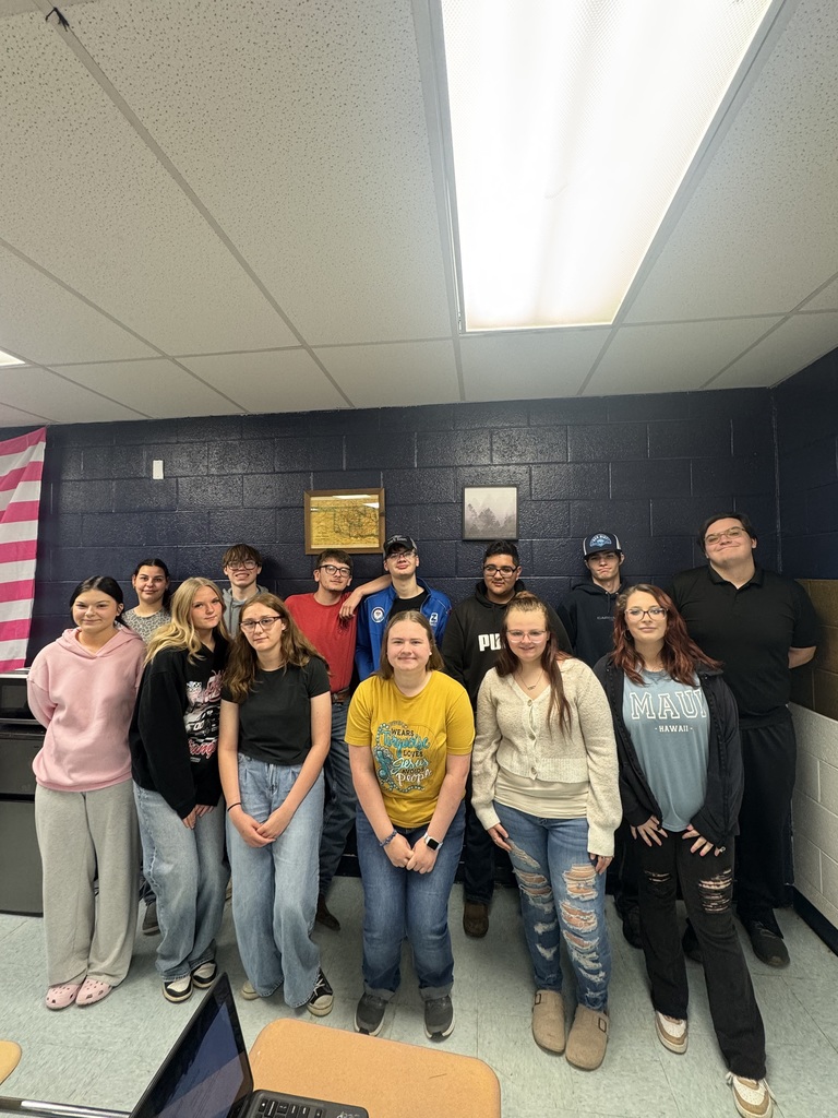 A group of people posing for a photo in a room with blue walls and a flag in the background.
