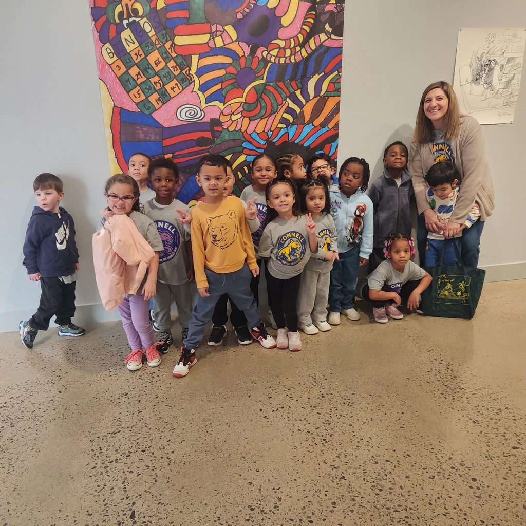 Kids and teacher posing in front of a colorful art piece in the Erie Art Museum. 