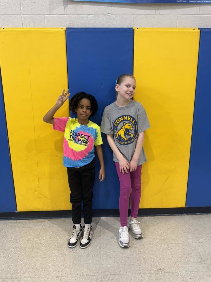 Two students posing and one student is holding up 3 fingers. 