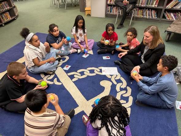 Students playing  an egg swap dice game with McKinley Principal, Mrs. Bull.