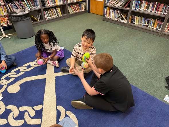 Students playing  an egg swap dice game with McKinley Principal, Mrs. Bull.