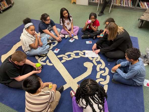 Students playing  an egg swap dice game with McKinley Principal, Mrs. Bull.