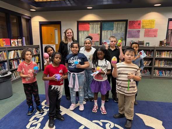 Students holding their eggs and standing with their principal, Mrs. Bull. 