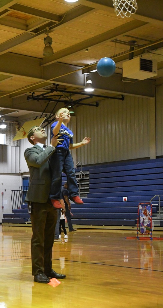 father helping his son shoot a basket