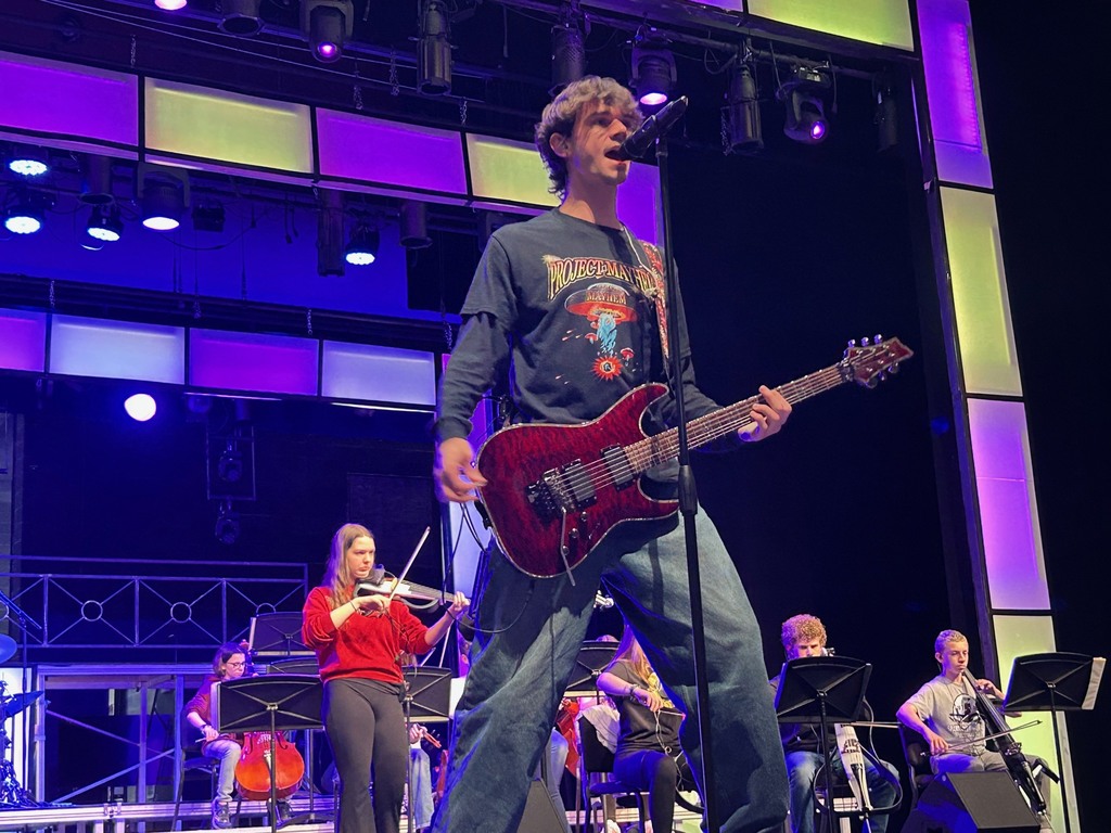 singer with guitar and violins behind on BPAC stage