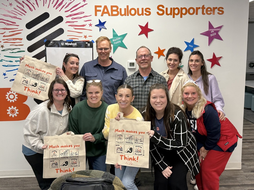 a group of math teachers smiling and showing math bags they received at a workshop