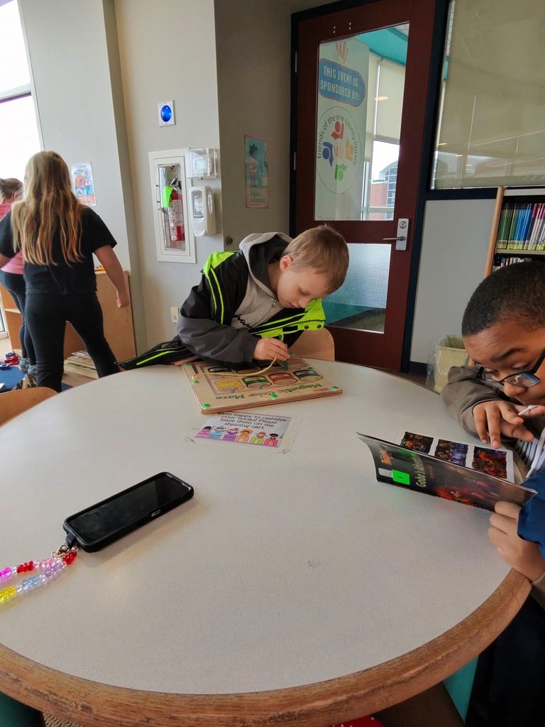 Kids are reading and playing an activity at a circular table in the children's library. 
