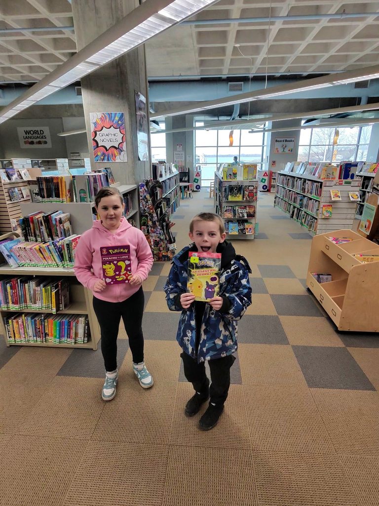 Kids holding books excitedly in the children's library. 
