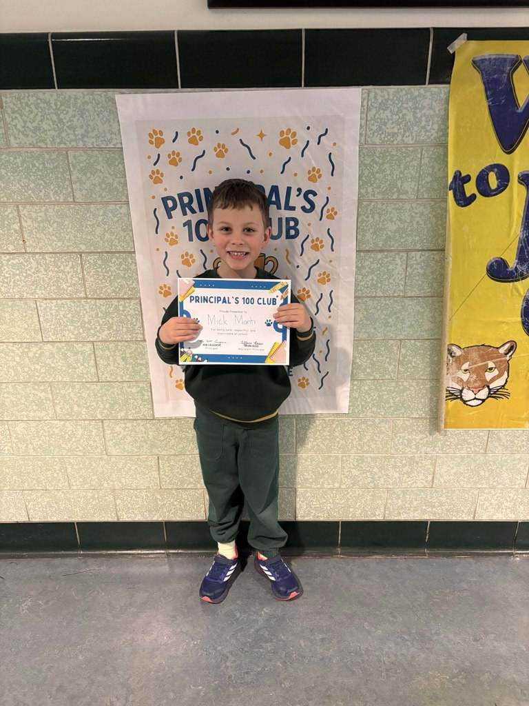 Young boy wearing a black shirt is holding his "Principal 100 Club" Certificate. 