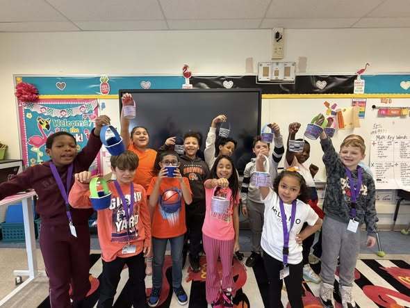 Students holding their baskets they just weaved in their classroom. 