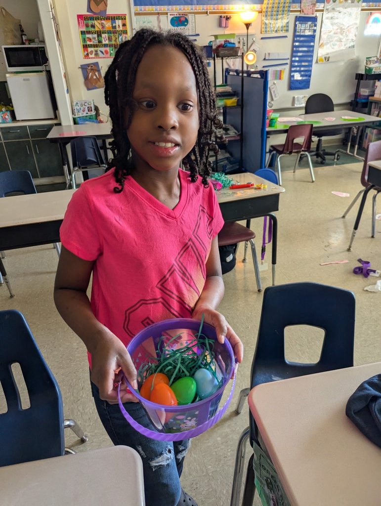 A student holding a purple basket with colorful easter eggs in it. 