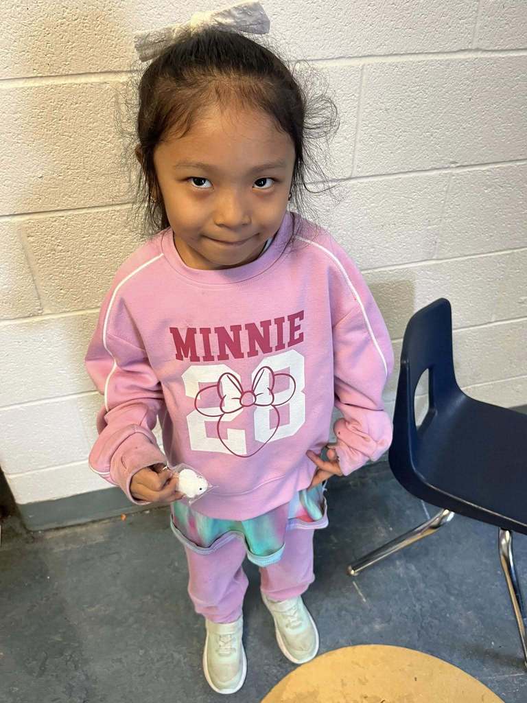 A young girl who is wearing a pink outfit is holding her squishy bingo prize. 