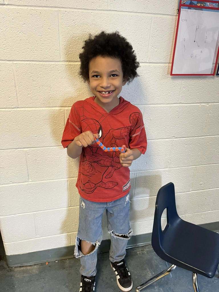 A young boy who is wearing a red spider man shirt is holding a blue and red fidget toy he won during bingo.