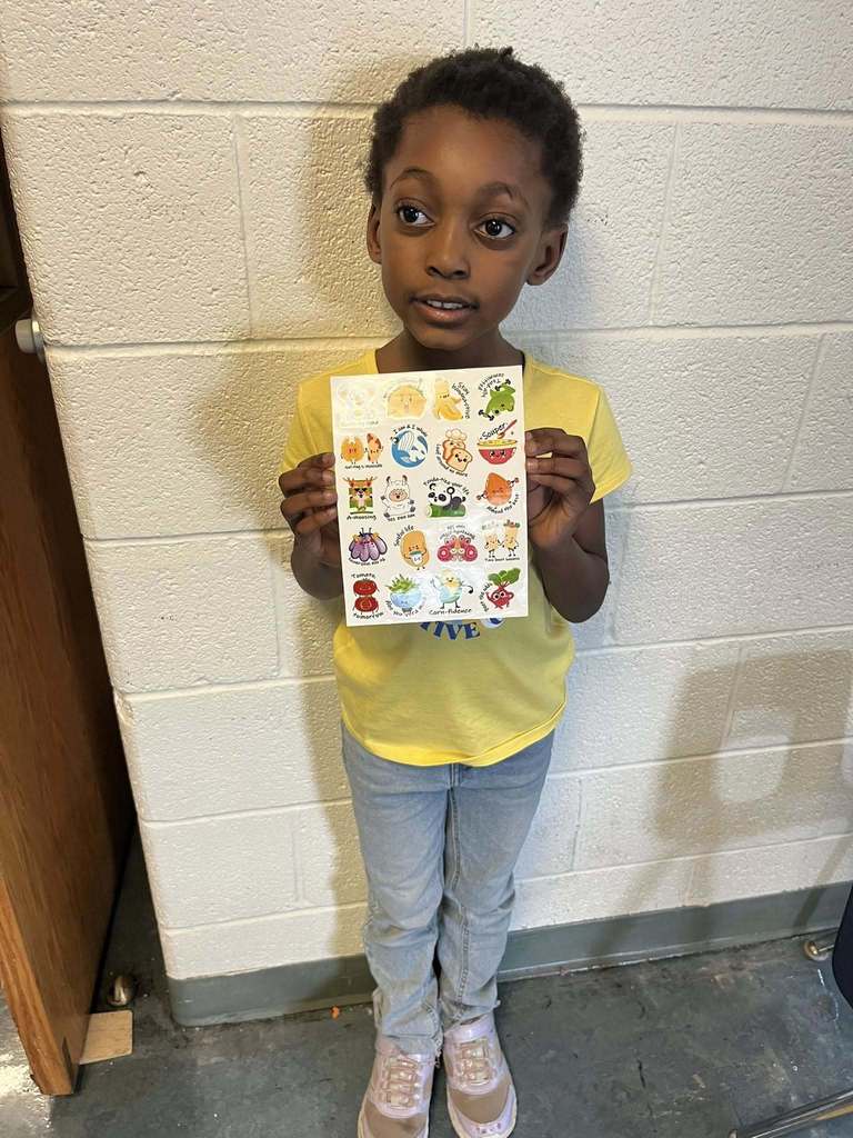A young boy who is wearing a yellow shirt is holding a sheet of stickers he won during bingo.