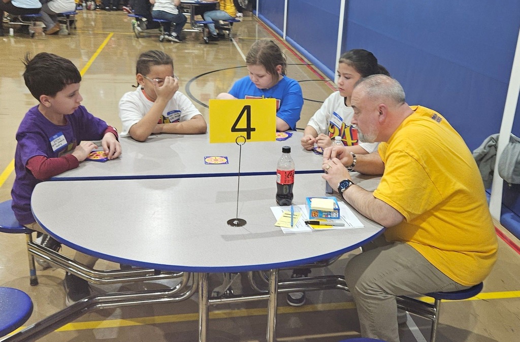 Students and adult at a circular table doing math.