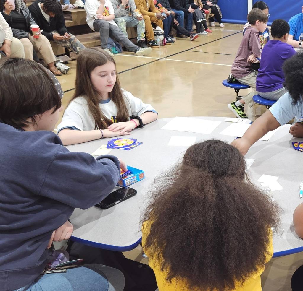 Students and adult at a circular table. 