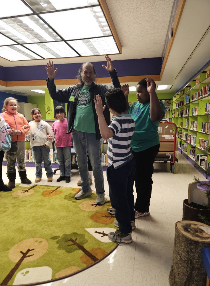 Robert Lewis is talking to students while a few students hold their hands up. 