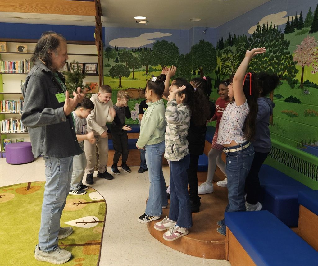 Robert Lewis is talking to students while the students raise their hands. 