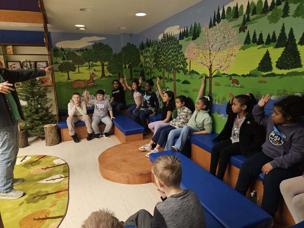 Robert Lewis is talking to students while students raise their hands. 