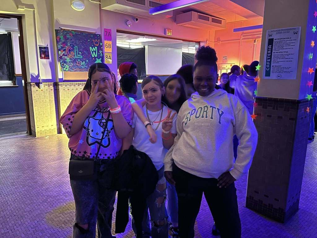 Students posing for a picture at their glow in the dark Q3 PBIS March Madness event.