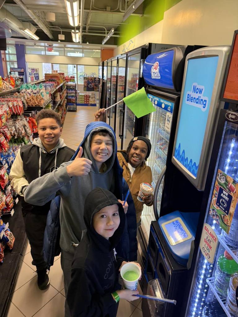 Students posing for aa photo while they get snacks at a gas station. 