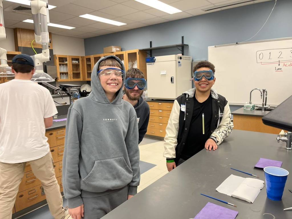 Students posing for a photo while they wear safety glasses. 