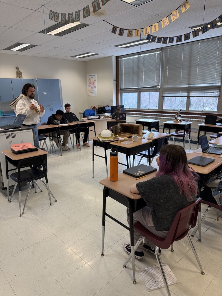A teacher is speaking to students in a classroom. 