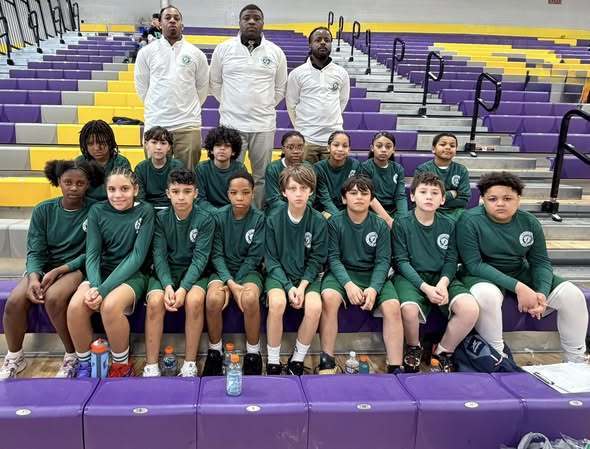Students wearing green matching team uniforms and three adult men standing behind them in white matching shirts. 