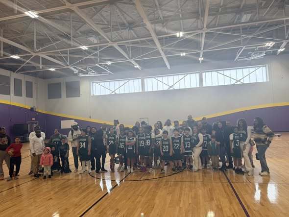 Students wearing green and adults are posing for a photo. 