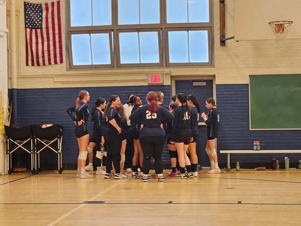 Wilson team wearing matching blue uniforms is huddling before the game. 