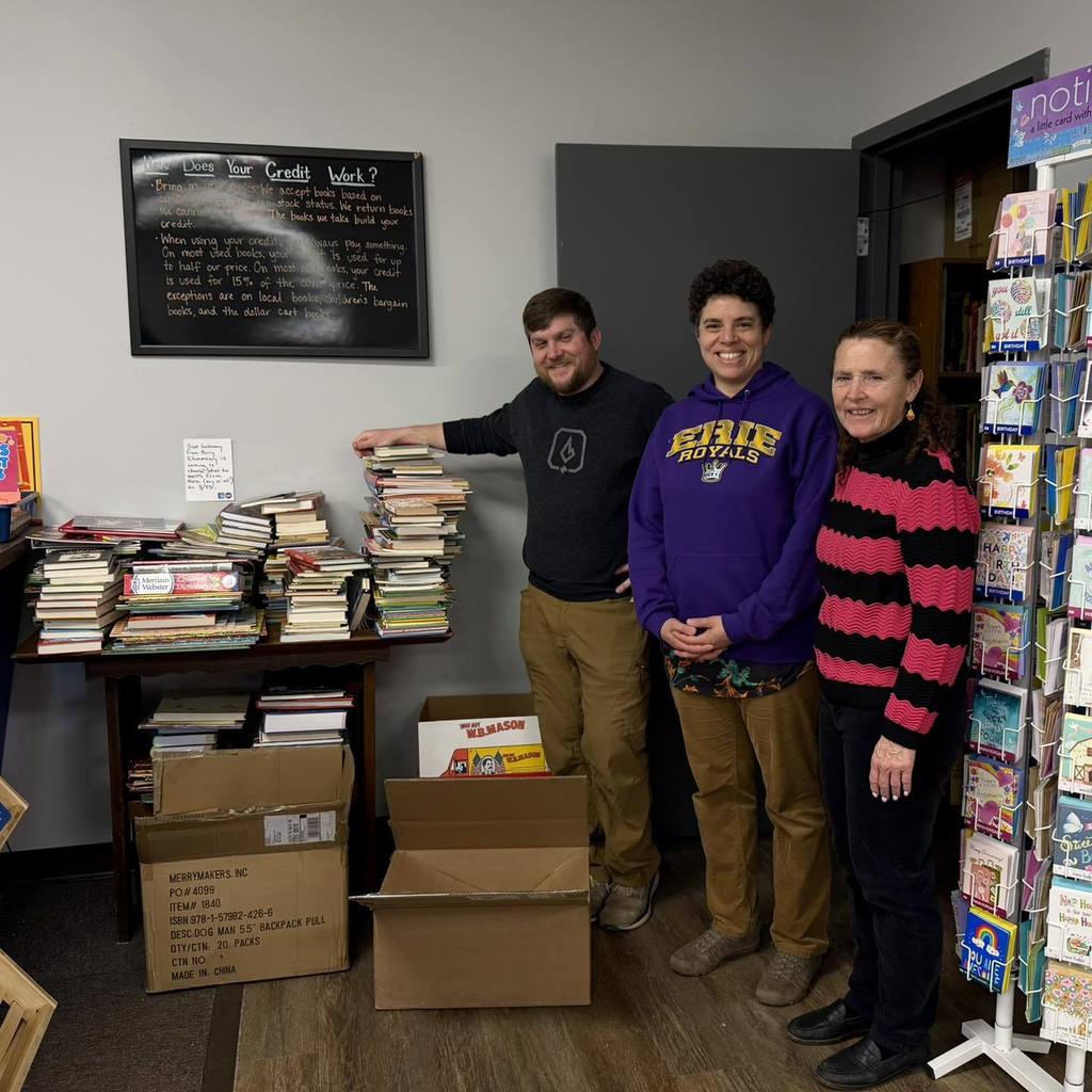 Adults standing next to books in a room. 