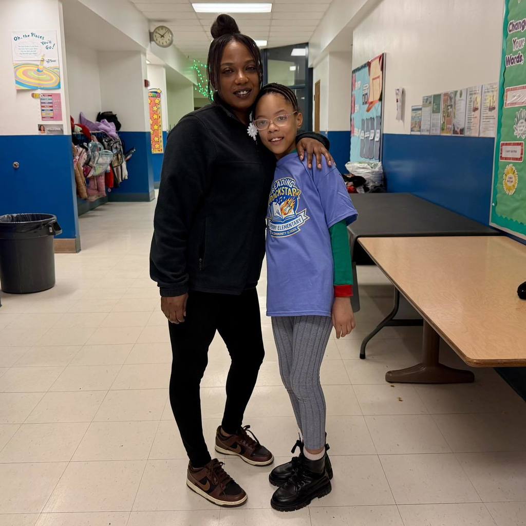 A student in a blue shirt is standing next to a man and smiling. 
