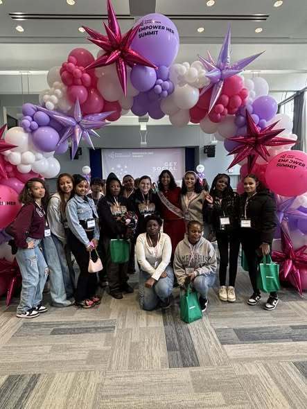 A group of women posing under a balloon arch.
