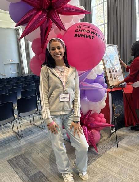 A young female posing inn front of a  balloon arch. 