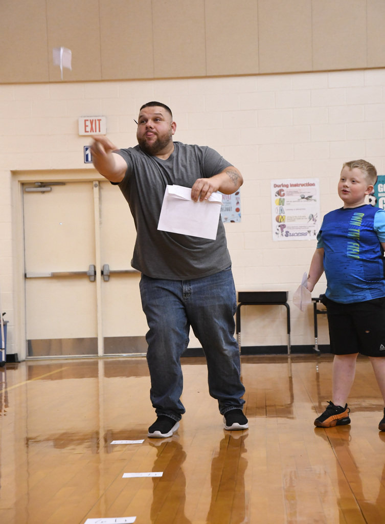 father tossing a paper airplane with son in competition