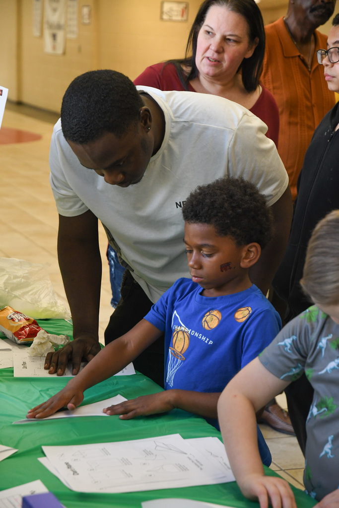 student and father folding a paper airplane