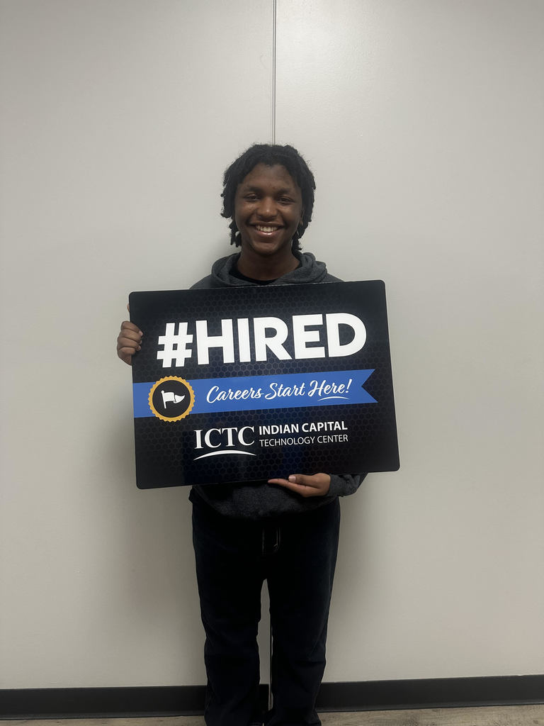 Person with dark hoodie holds sign that says "#HIRED Careers Start Here!" and logo. White background.