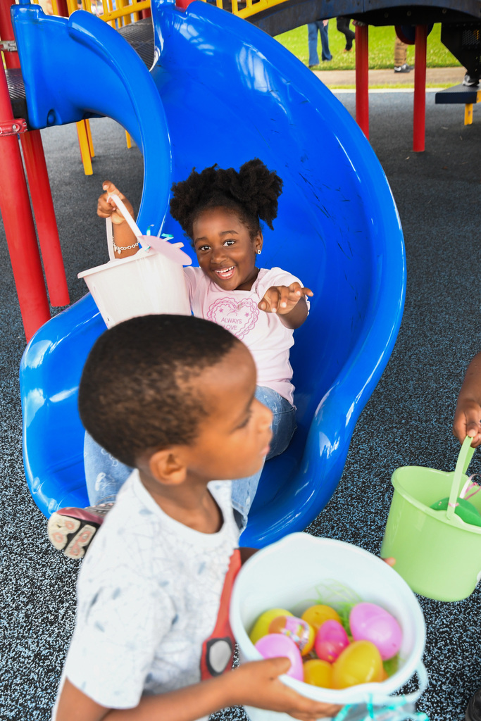 girl going down a slide with a basket of eastereggs