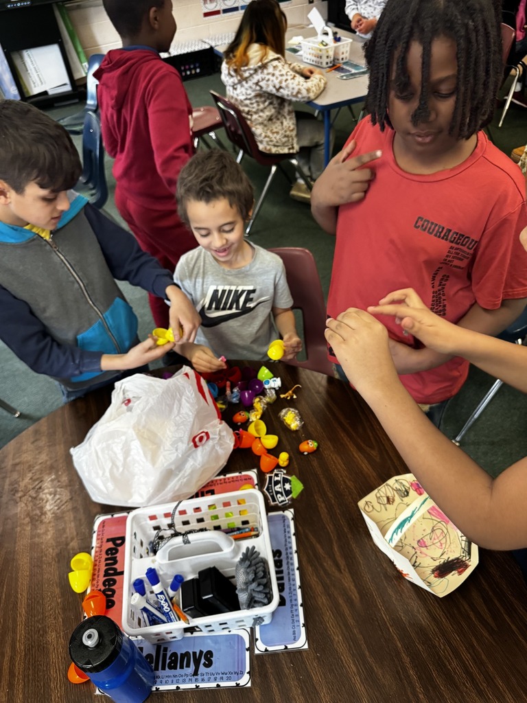 Students opening plastic eggs on a table.