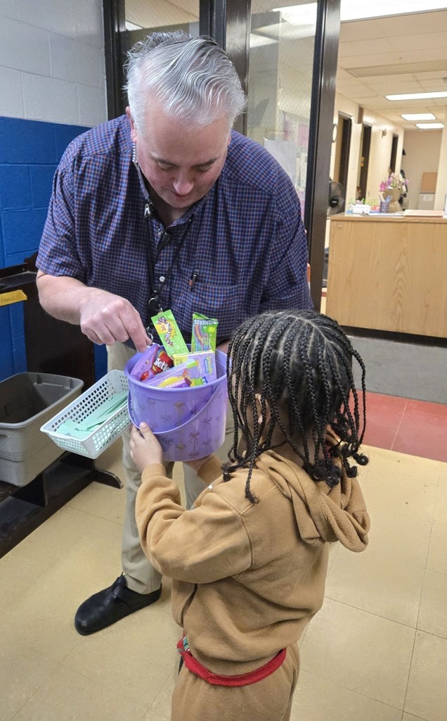 The Assistant Principal giving a student a purple easter basket. 