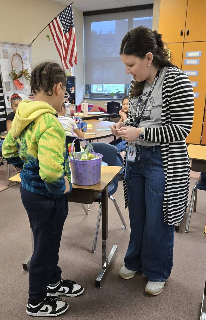 A teacher and student looking at a purple easter basket in class. 