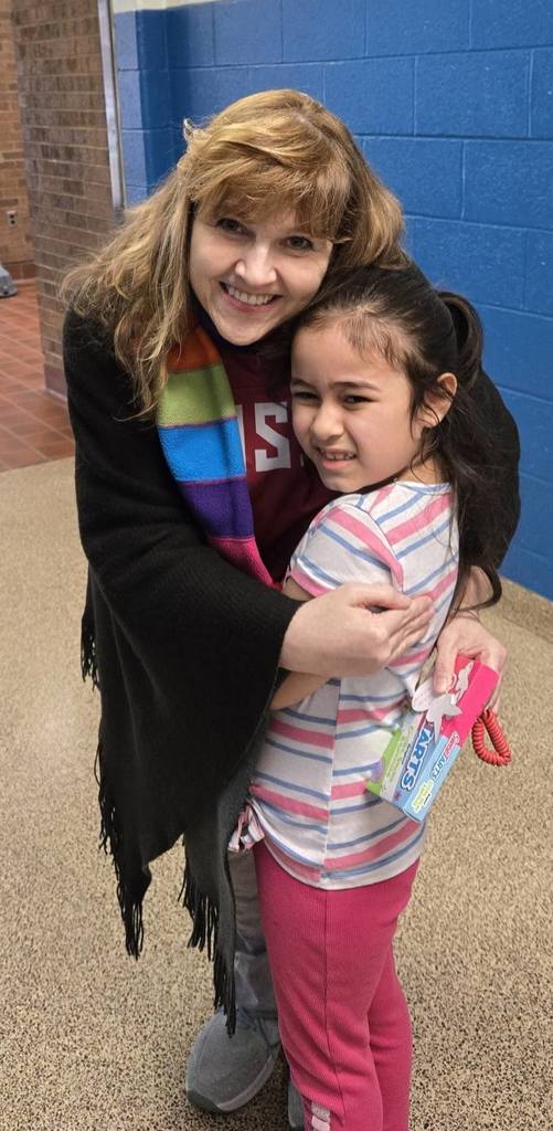 A teacher hugging a student dressed in pink. 