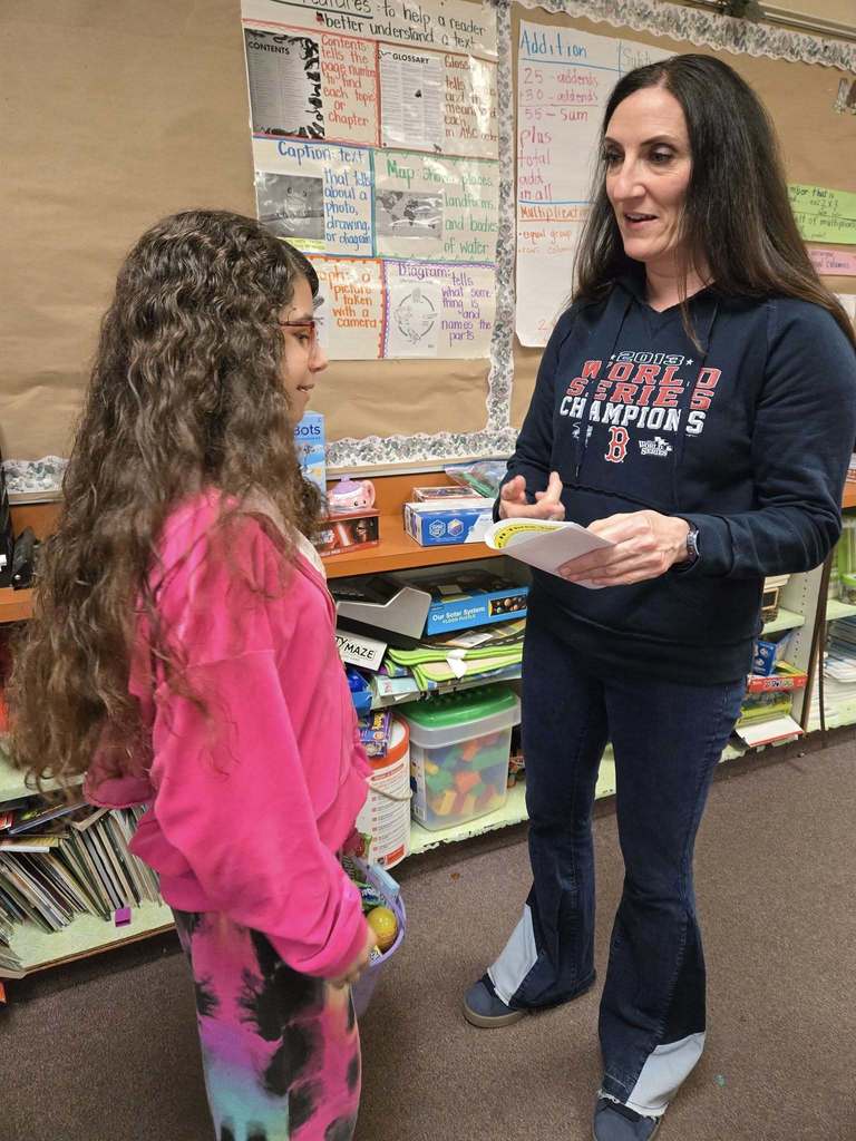 A teacher talking to a student who is holding her easter basket. 