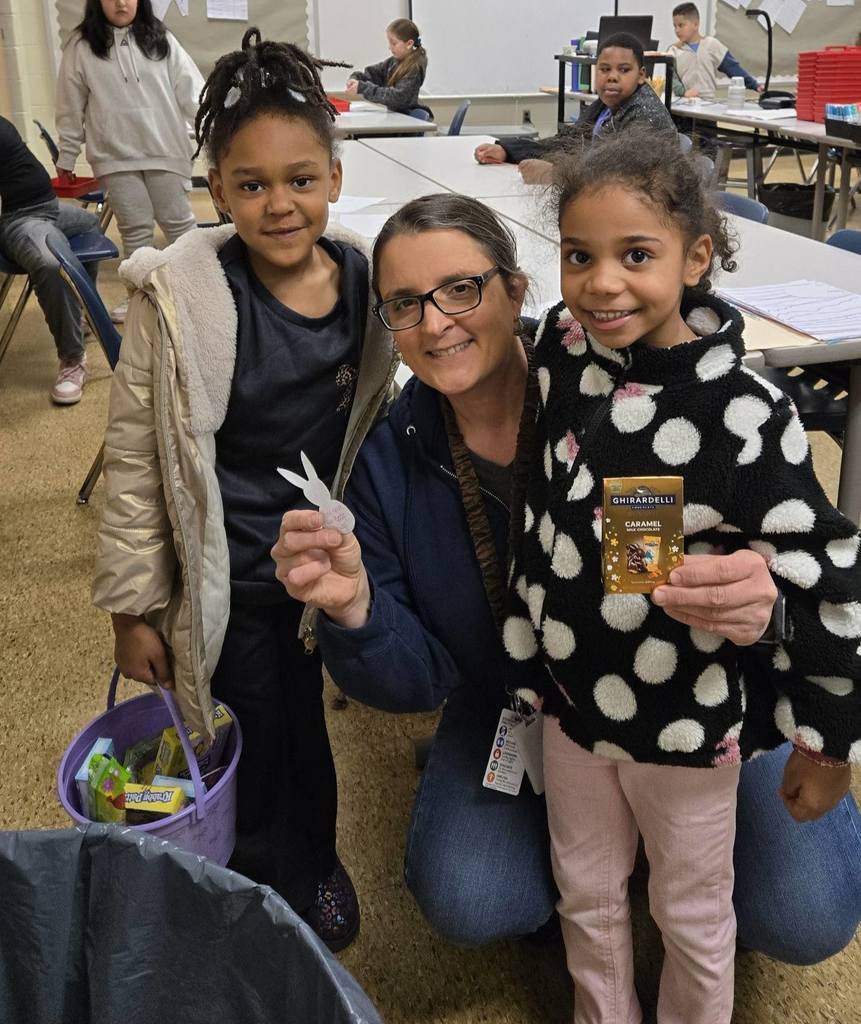 Teacher and students are posing while holding candy and an easter basket. 