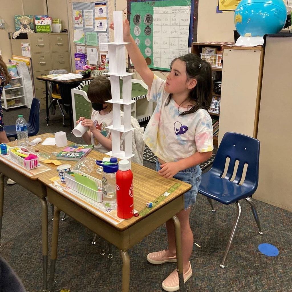 little girl builds tower in class