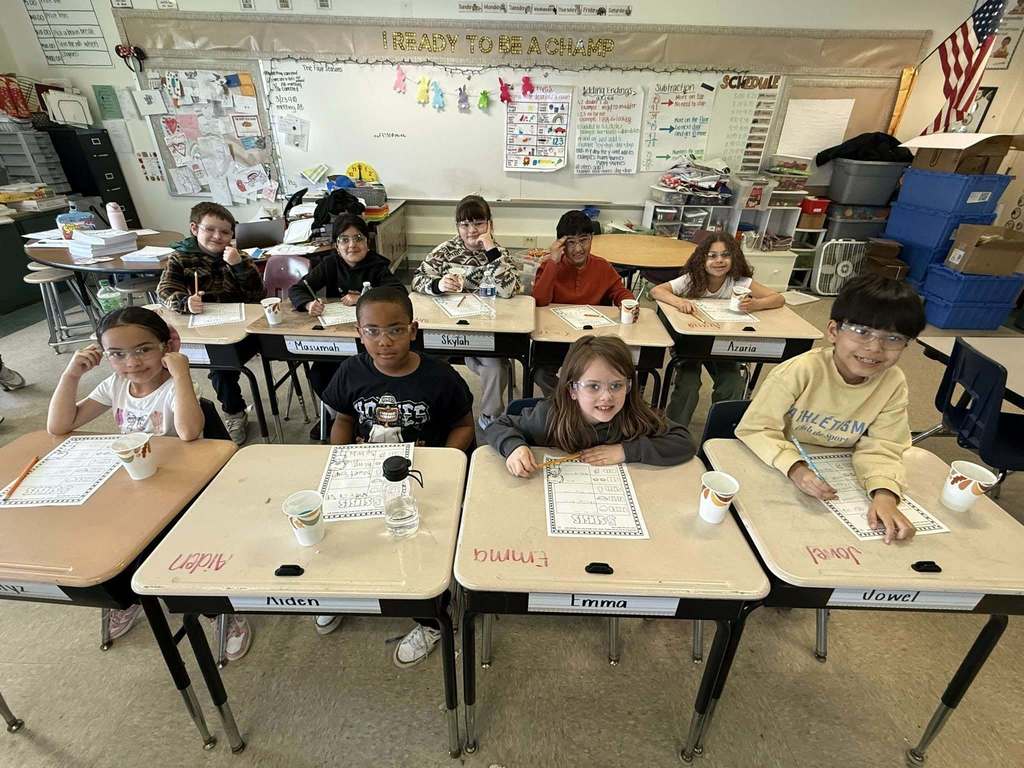 Kids posing at their tables in class. 